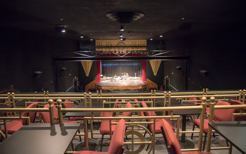 View of the Elbert Theatre stage in Elberton, GA, seen from a balcony level featuring rows of tables and red chairs.